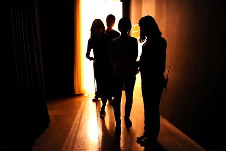 A picture of visitors meeting the guide in the double door to enter the dark.
