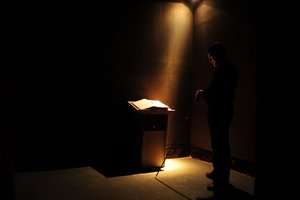 Foto eines Stehpults mit dem Gästebuch, erleuchtet nur von einem Lichtstrahl. a single beam in the dark at the Dialogo con Oscuridad, Monterrey
