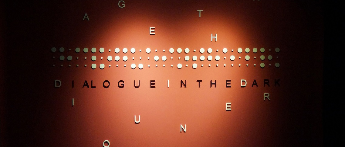 Photo of a wall with Dialogue in the Dark written in braille.